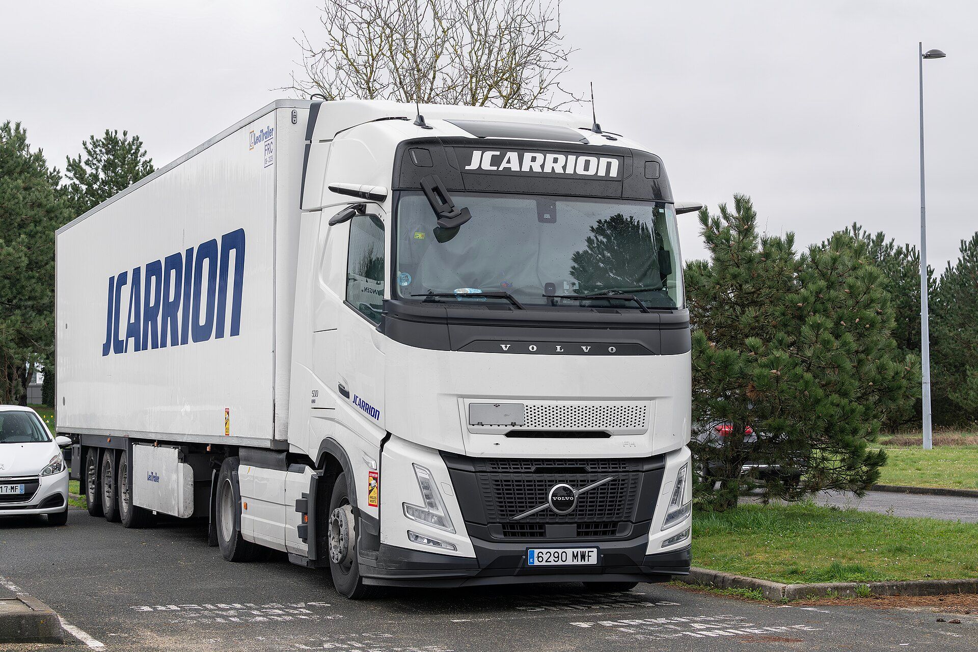 White Volvo FH Aero tractor unit with an extended rounded front end, coupled to a box semi-trailer