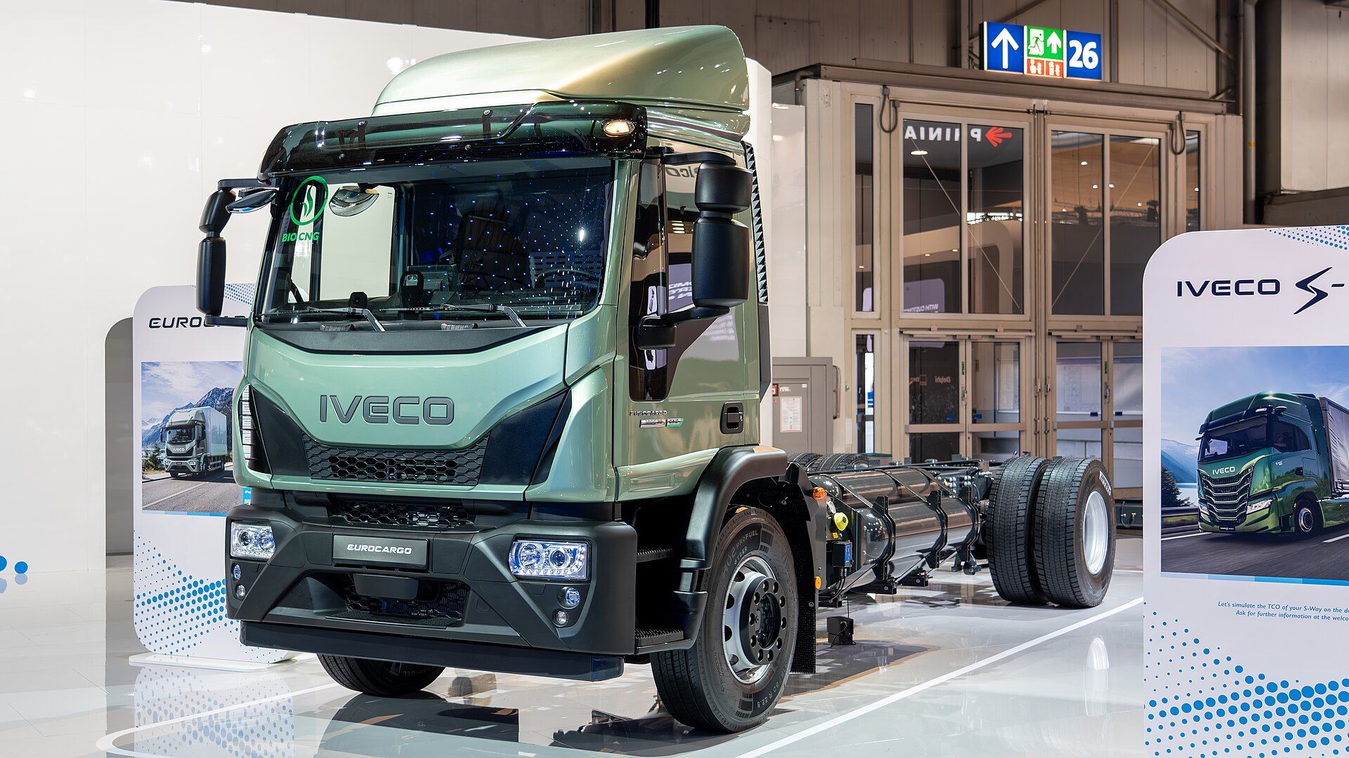 Green Iveco Eurocargo CNG chassis cab with a bio-CNG windscreen sticker and gas cylinders along the bare frame, on the IVECO stand at IAA Transportation 2024