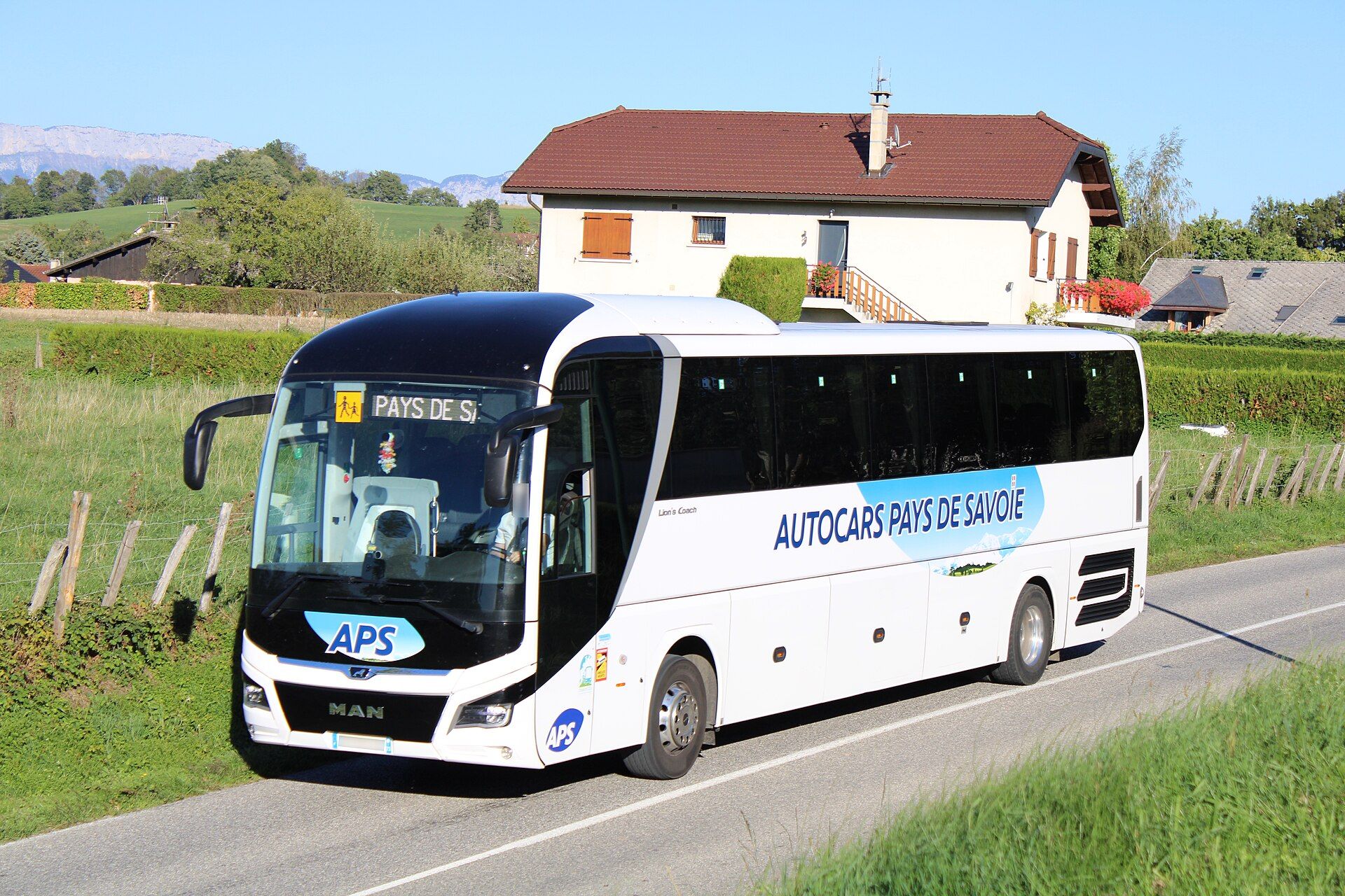 White MAN touring coach in Autocars Pays de Savoie livery on a rural road near Marcellaz-Albanais, France, with the Lion's Coach model script on its flank