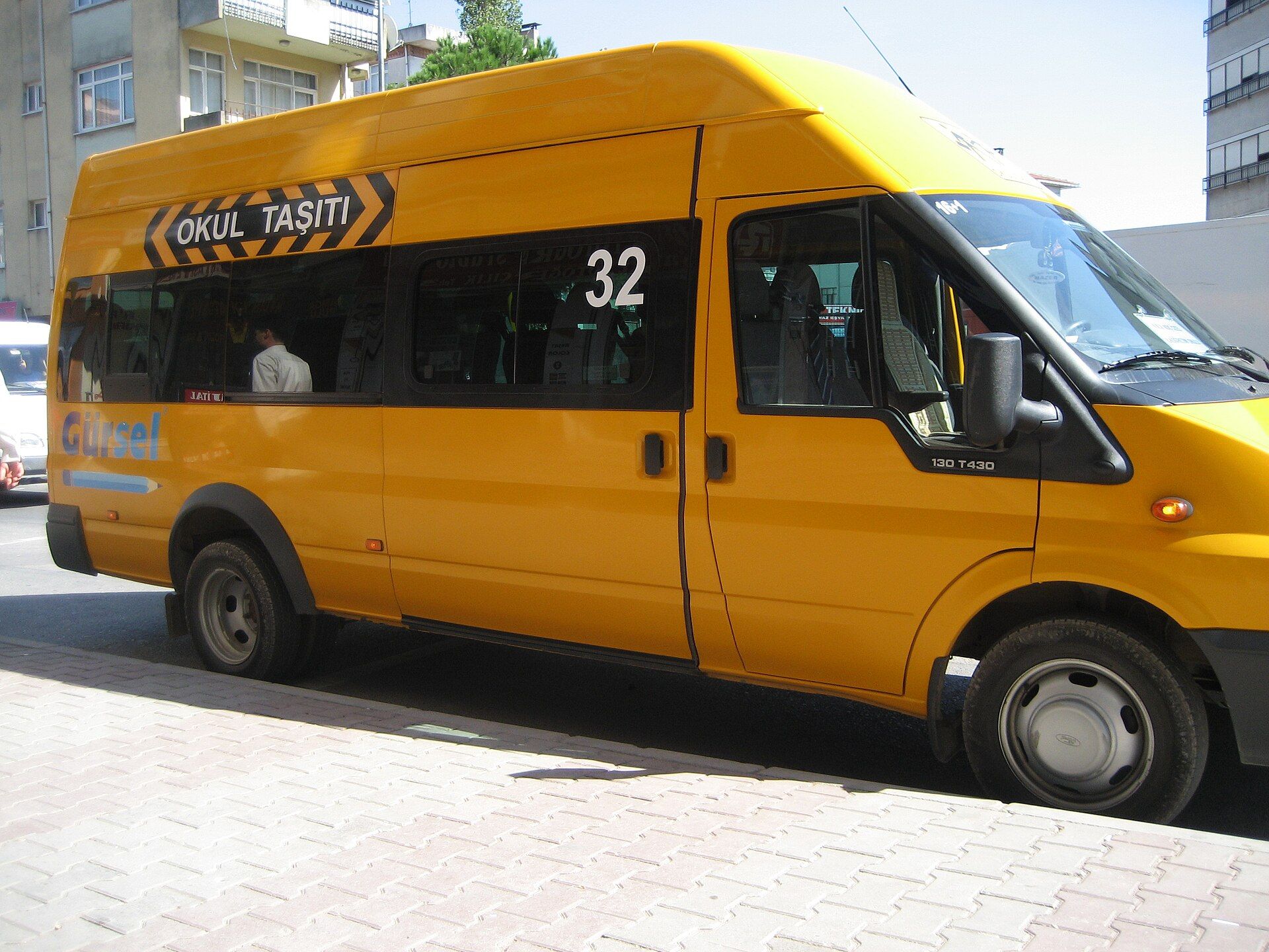 Yellow Ford Transit minibus in Istanbul carrying an OKUL TAŞITI school-vehicle band above the windows