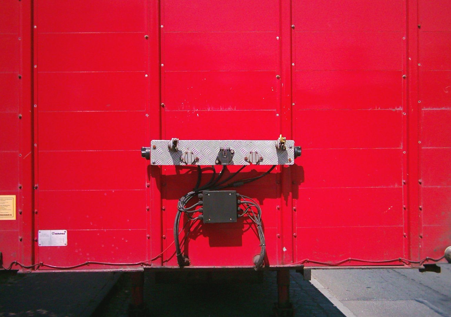 Brake and electrical connection panel with two air coupling heads on the front bulkhead of a red Krone trailer