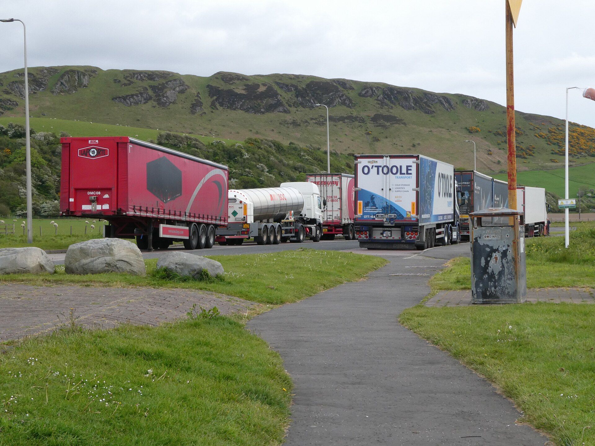 Lorry park with a red curtainsider semi-trailer, a white tank semi-trailer and an insulated box semi-trailer parked in line