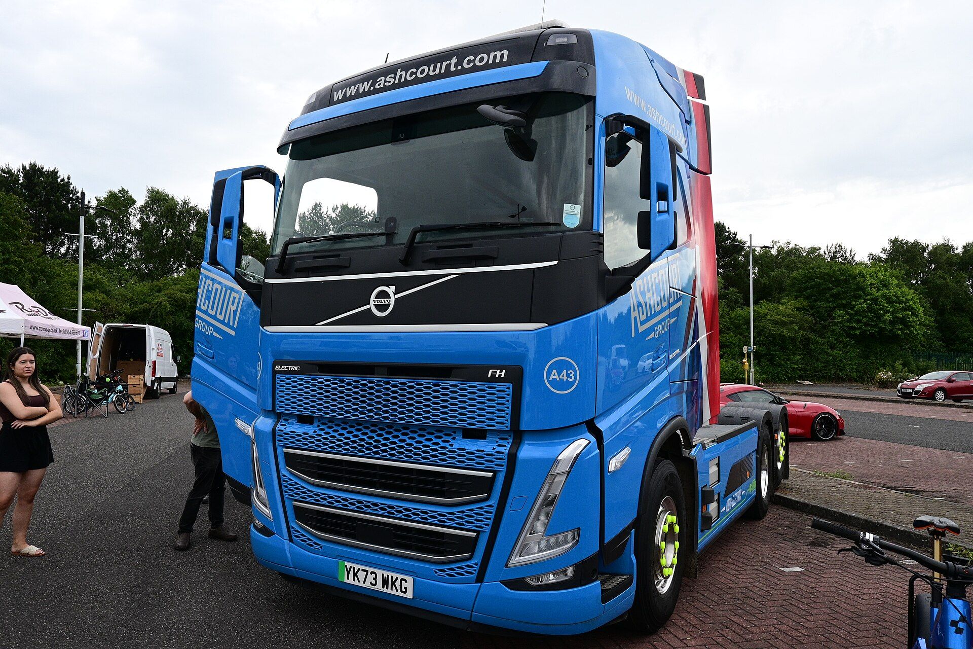 Blue Volvo FH Electric tractor unit with a lifted tag axle at an electric vehicle event in Kingston upon Hull